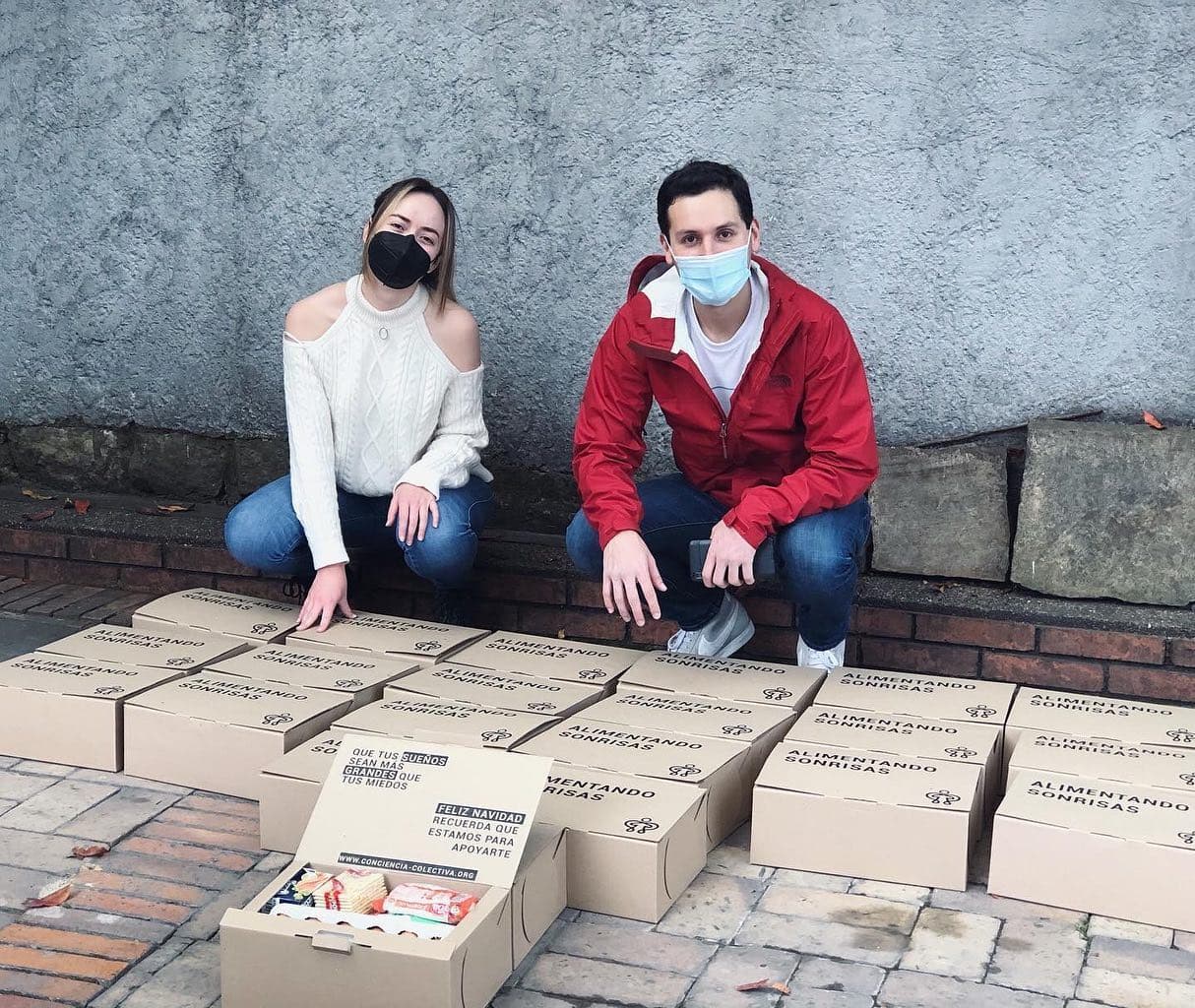 Pareja con tapabocas junto a cajas de donación